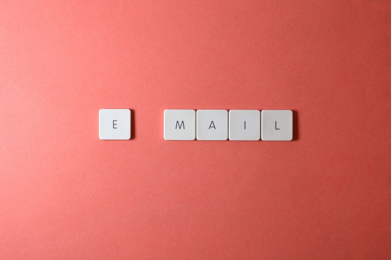Vue à plat de touches de clavier formant le mot email sur un fond corail.